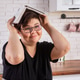Woman with brown hair in cozy kitchen, holding book and cup, looking contemplative. Woman with brown hair in cozy kitchen, holding book and cup, looking contemplative. - PhotoDune Item for Sale