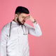 Tired male doctor wearing white uniform, standing with closed eyes, touching nose. Tired male doctor wearing white uniform, standing with closed eyes, touching nose. - PhotoDune Item for Sale