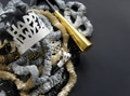 Happy New Year flat lay with tiara on textured leis next to horn on dark background with copy space Happy New Year flat lay with tiara on textured leis next to horn on dark background with copy space - PhotoDune Item for Sale