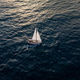 Aerial video of a white sailboat sailing alone on deep blue sea. Calm waves shimmer under sunlight. Aerial video of a white sailboat sailing alone on deep blue sea. Calm waves shimmer under sunlight. - PhotoDune Item for Sale