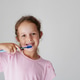 A smiling little girl in a pink t-shirt is brushing her teeth with a blue toothbrush A smiling little girl in a pink t-shirt is brushing her teeth with a blue toothbrush - PhotoDune Item for Sale