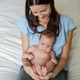 Pretty young mother sitting on bed in light bedroom at home and holding her cute newborn baby Pretty young mother sitting on bed in light bedroom at home and holding her cute newborn baby - PhotoDune Item for Sale