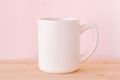 Beige big ceramic mug with empty space for your design standing on wooden table above pink wall. Beige big ceramic mug with empty space for your design standing on wooden table above pink wall. - PhotoDune Item for Sale