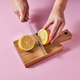 Woman's hands cut a lemon on a wooden board with a knife around a pink background with copy Woman's hands cut a lemon on a wooden board with a knife around a pink background with copy - PhotoDune Item for Sale