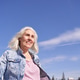 Mature caucasian woman smiling outdoors in denim jacket under clear blue sky Mature caucasian woman smiling outdoors in denim jacket under clear blue sky - PhotoDune Item for Sale