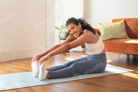 woman exercising doing seated toe touch in living room Stock Photo