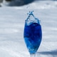 Blue color splashing out of a glass with egg on snow background Blue color splashing out of a glass with egg on snow background - PhotoDune Item for Sale