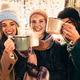 Joyful friends cheering with hot drinks at Christmas market under festive lights. Joyful friends cheering with hot drinks at Christmas market under festive lights. - PhotoDune Item for Sale