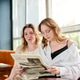 Young women reading newspaper together in bright cafe Young women reading newspaper together in bright cafe - PhotoDune Item for Sale