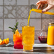 Two glasses with yellow mango juice and red syrup. The drinks are decorated with juniper sprigs. Two glasses with yellow mango juice and red syrup. The drinks are decorated with juniper sprigs. - PhotoDune Item for Sale