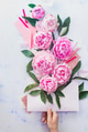 Hand holding an envelope full of pink flowers with pencils and notes on a light background Hand holding an envelope full of pink flowers with pencils and notes on a light background - PhotoDune Item for Sale