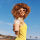 Cheerful young woman with curly hair holding a smoothie on a sunny day with a blue sky and palm Cheerful young woman with curly hair holding a smoothie on a sunny day with a blue sky and palm - PhotoDune Item for Sale