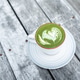 Cup of fresh green matcha latte beverage with latte art on foam. Background of wooden table Cup of fresh green matcha latte beverage with latte art on foam. Background of wooden table - PhotoDune Item for Sale