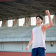 Asian man in white tank top is closing eyes and raising a fist while standing on racetrack. Asian man in white tank top is closing eyes and raising a fist while standing on racetrack. - PhotoDune Item for Sale
