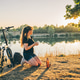 Woman drinking coffee by lake at sunrise Woman drinking coffee by lake at sunrise - PhotoDune Item for Sale