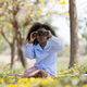 African Girl Using Binoculars Sitting in Yellow Flower Field Exploring Nature African Girl Using Binoculars Sitting in Yellow Flower Field Exploring Nature - PhotoDune Item for Sale