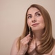 Woman with long brown hair is thoughtfully using a facial roller on her cheek Woman with long brown hair is thoughtfully using a facial roller on her cheek - PhotoDune Item for Sale