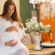 Smiling pregnant woman in a bright room wearing a white lace maternity dress Smiling pregnant woman in a bright room wearing a white lace maternity dress - PhotoDune Item for Sale