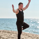 Young man practicing beach yoga in tree pose by Baltic Sea Young man practicing beach yoga in tree pose by Baltic Sea - PhotoDune Item for Sale
