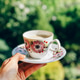 Woman holding floral teacup with green bokeh background Woman holding floral teacup with green bokeh background - PhotoDune Item for Sale