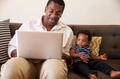 Grandfather And Grandson Sit On Sofa At Home Using Laptop Grandfather And Grandson Sit On Sofa At Home Using Laptop - PhotoDune Item for Sale