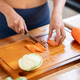 Close up sportswear woman holding knife chopping carrot on cutting board at kitchen cooking counter. Close up sportswear woman holding knife chopping carrot on cutting board at kitchen cooking counter. - PhotoDune Item for Sale