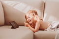 Cute toddler girl on coach, kids using technologies, child watchimg certoons, expression Cute toddler girl on coach, kids using technologies, child watchimg certoons, expression - PhotoDune Item for Sale