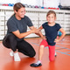 Girl performing a corrective motoric balance exercise on a stability disc while a trainer assists Girl performing a corrective motoric balance exercise on a stability disc while a trainer assists - PhotoDune Item for Sale