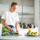 Young woman in white t-shirt and blue jeans cooking healthy food with cucumber in kitchen at home Young woman in white t-shirt and blue jeans cooking healthy food with cucumber in kitchen at home - PhotoDune Item for Sale
