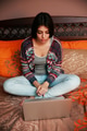 Young beautiful woman sitting on the bed and looking at laptop Young beautiful woman sitting on the bed and looking at laptop - PhotoDune Item for Sale