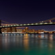 Manhattan Bridge lights shine over water at night with NY city skyline in background Manhattan Bridge lights shine over water at night with NY city skyline in background - PhotoDune Item for Sale