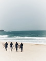 Four surfers walking with their boards against a golden sandy beach with rough surf on the beach Four surfers walking with their boards against a golden sandy beach with rough surf on the beach - PhotoDune Item for Sale