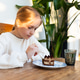 Young girl eating a slice of layered chocolate cake at a wooden table in a cozy indoor setting Young girl eating a slice of layered chocolate cake at a wooden table in a cozy indoor setting - PhotoDune Item for Sale