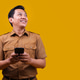 Asian Man in Official Khaki Workwear Looking at Copy Space and Holding Cellphone Asian Man in Official Khaki Workwear Looking at Copy Space and Holding Cellphone - PhotoDune Item for Sale