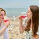Young girlfriends enjoying pink wine at beach picnic by sea during daytime Young girlfriends enjoying pink wine at beach picnic by sea during daytime - PhotoDune Item for Sale