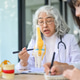 Old asian woman physician talking teaching on bone model and young doctor taking note at exam table. Old asian woman physician talking teaching on bone model and young doctor taking note at exam table. - PhotoDune Item for Sale