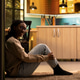 Portrait of smiling black woman sitting on the floor in cozy clothes for comfort Portrait of smiling black woman sitting on the floor in cozy clothes for comfort - PhotoDune Item for Sale