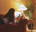Young woman laying in a sofa using technology while reading her tablet. Young woman laying in a sofa using technology while reading her tablet. - PhotoDune Item for Sale