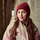 Young woman with long brown hair wearing red knit hat and soft pastel scarf in rustic corridor Young woman with long brown hair wearing red knit hat and soft pastel scarf in rustic corridor - PhotoDune Item for Sale