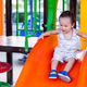 Joyful toddler successfully sliding down a vibrant orange slide at an outdoor playground. Joyful toddler successfully sliding down a vibrant orange slide at an outdoor playground. - PhotoDune Item for Sale