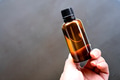 Hand holding a amber glass bottles on grey background Hand holding a amber glass bottles on grey background - PhotoDune Item for Sale