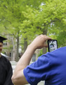 A Dad snapping photos of his graduating son wearing cap & gown regalia in college campus graduation A Dad snapping photos of his graduating son wearing cap & gown regalia in college campus graduation - PhotoDune Item for Sale