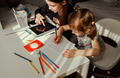 Two sisters sitting at table drawing, using gadgets. Day natural sunlight. Home activities for kids Two sisters sitting at table drawing, using gadgets. Day natural sunlight. Home activities for kids - PhotoDune Item for Sale
