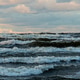 Waves crashing on a beach under a cloudy sky during sunset Waves crashing on a beach under a cloudy sky during sunset - PhotoDune Item for Sale