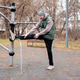 A man in a tracksuit and hat stretches on an outdoor sports ground. A man in a tracksuit and hat stretches on an outdoor sports ground. - PhotoDune Item for Sale