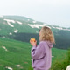 A woman with a yellow mug in her hands in the mountains. A woman with a yellow mug in her hands in the mountains. - PhotoDune Item for Sale