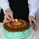 A young Caucasian girl lights a candle on her birthday cake. She's celebrating her birthday. A young Caucasian girl lights a candle on her birthday cake. She's celebrating her birthday. - PhotoDune Item for Sale