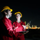 Workers discuss project details at night in an industrial area with lights in the background Workers discuss project details at night in an industrial area with lights in the background - PhotoDune Item for Sale