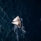 Aerial video of a white sailboat sailing alone on deep blue sea. Calm waves shimmer under sunlight. Aerial video of a white sailboat sailing alone on deep blue sea. Calm waves shimmer under sunlight. - PhotoDune Item for Sale