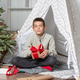 A teen child wraps Christmas gifts surprises in kraft paper with a rope, red ribbons A teen child wraps Christmas gifts surprises in kraft paper with a rope, red ribbons - PhotoDune Item for Sale